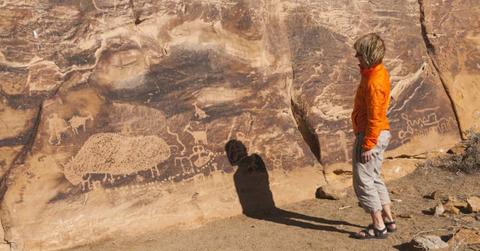 A person looking at rock carvings in an arid desert region. (Representative Cover Image Source: Getty Images | John Elk III)