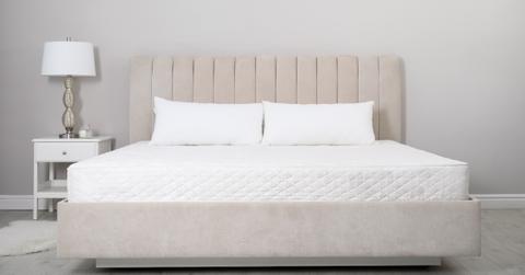 Comfortable bed with soft white mattress and pillows indoors