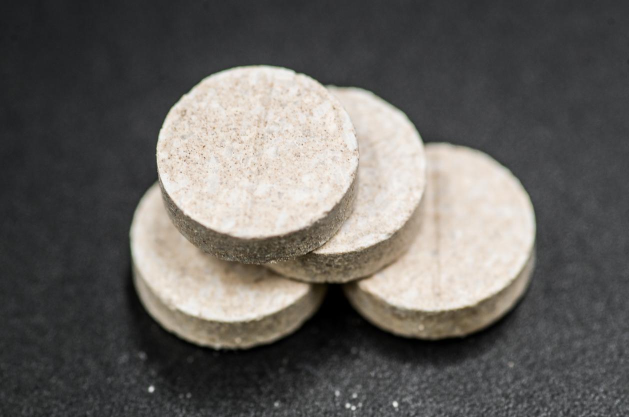 Four tan calcium carbonate tablets are stacked atop one another.