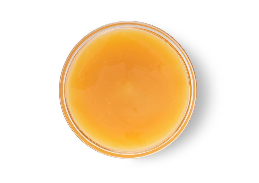 An overhead view of a glass of orange liquid.