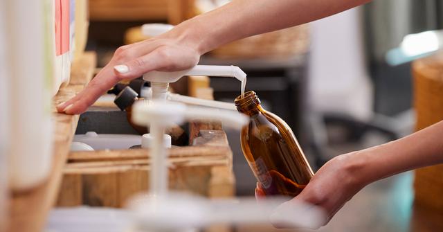 A person refilling a bottle with liquid soap.