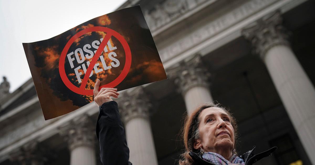 Woman holds anti fossil fuels sign at climate change protest