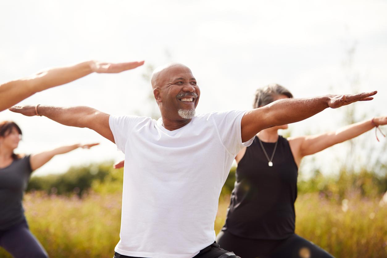 A group of smiling older adults exercise outdoors together.