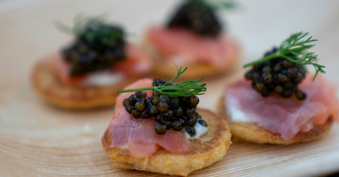 Caviar sits on crackers topped with other meat and toppings
