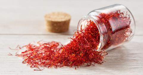 Saffron spilling out of a glass jar onto a wooden table.