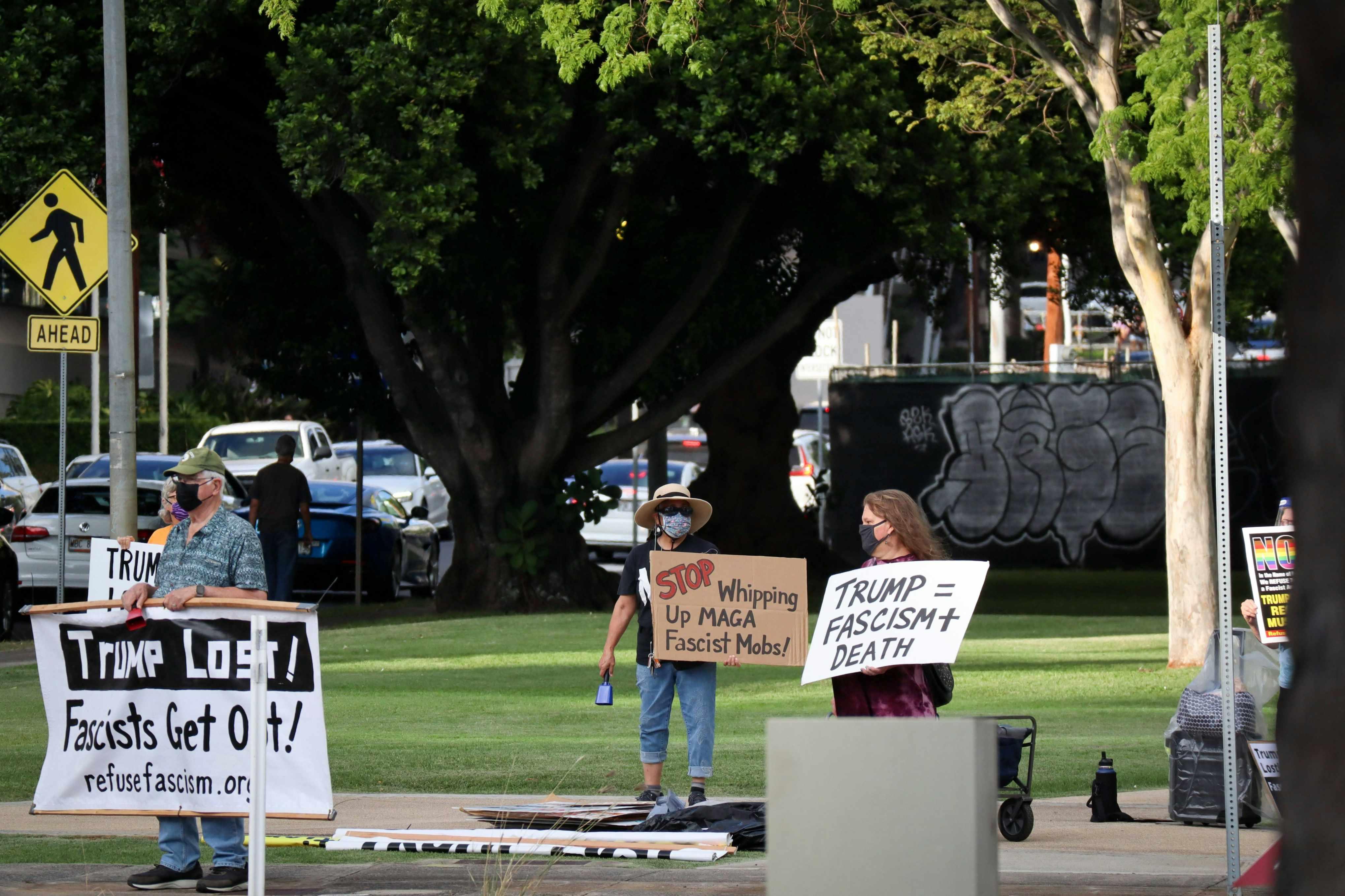Protestors stand with signs protesting Donald Trump.