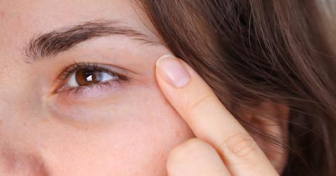 Close-up photo of a woman holding her pointer finger up to her under-eye area