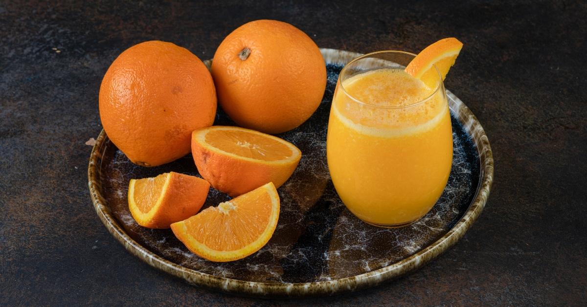 Plate of sliced oranges with a glass of orange juice next to it. 