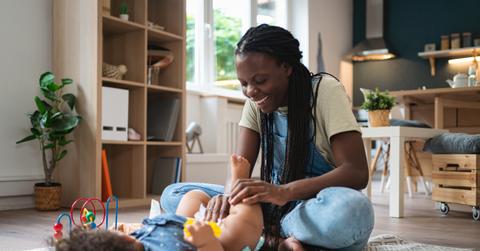 A smiling mother wipes her baby's body using a homemade wipe.