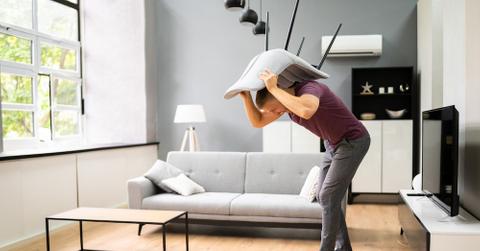 A man discovering roaches under a chair in a living room.