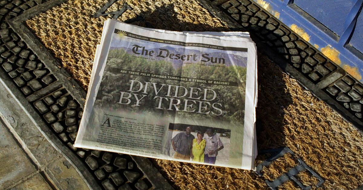 'The Desert Sun' newspaper on a welcome mat displaying the headline "Divided by Trees"