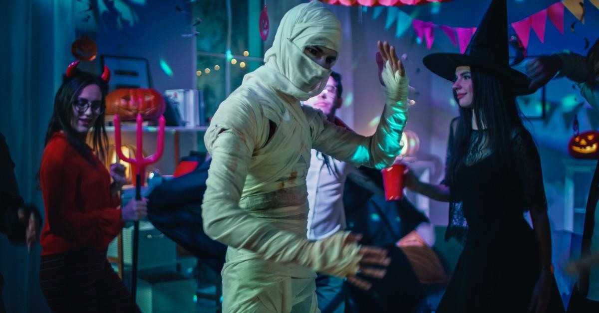 A man dressed as a mummy dances during a Halloween party with other costumed friends