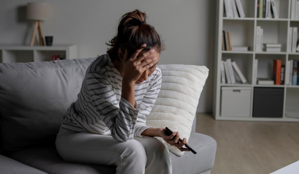 A woman with her head in her hands while watching TV.