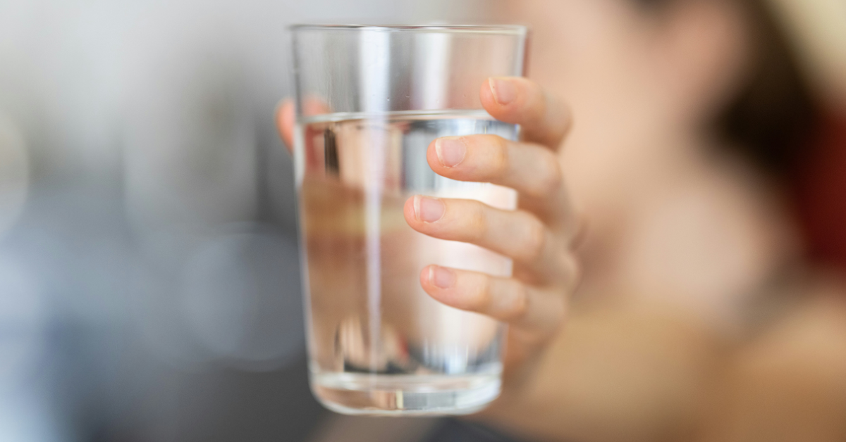A woman holds a glass of water in her hand