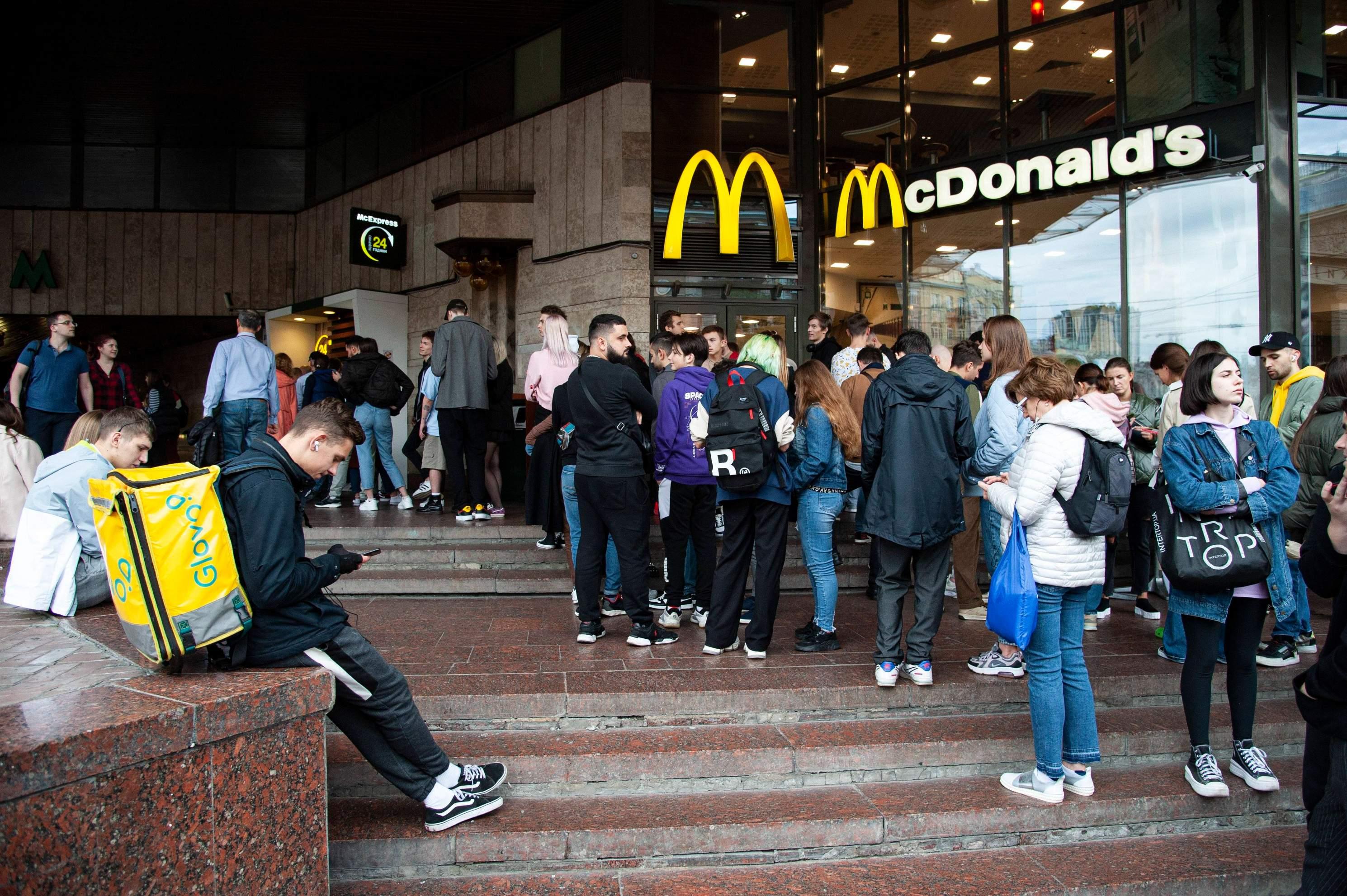 Customers of all ages line up outside a McDonald's store at night.