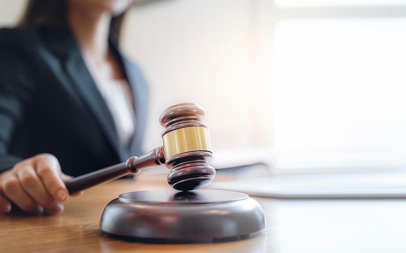 A blurred judge is pictured banging her gavel in a courtroom.