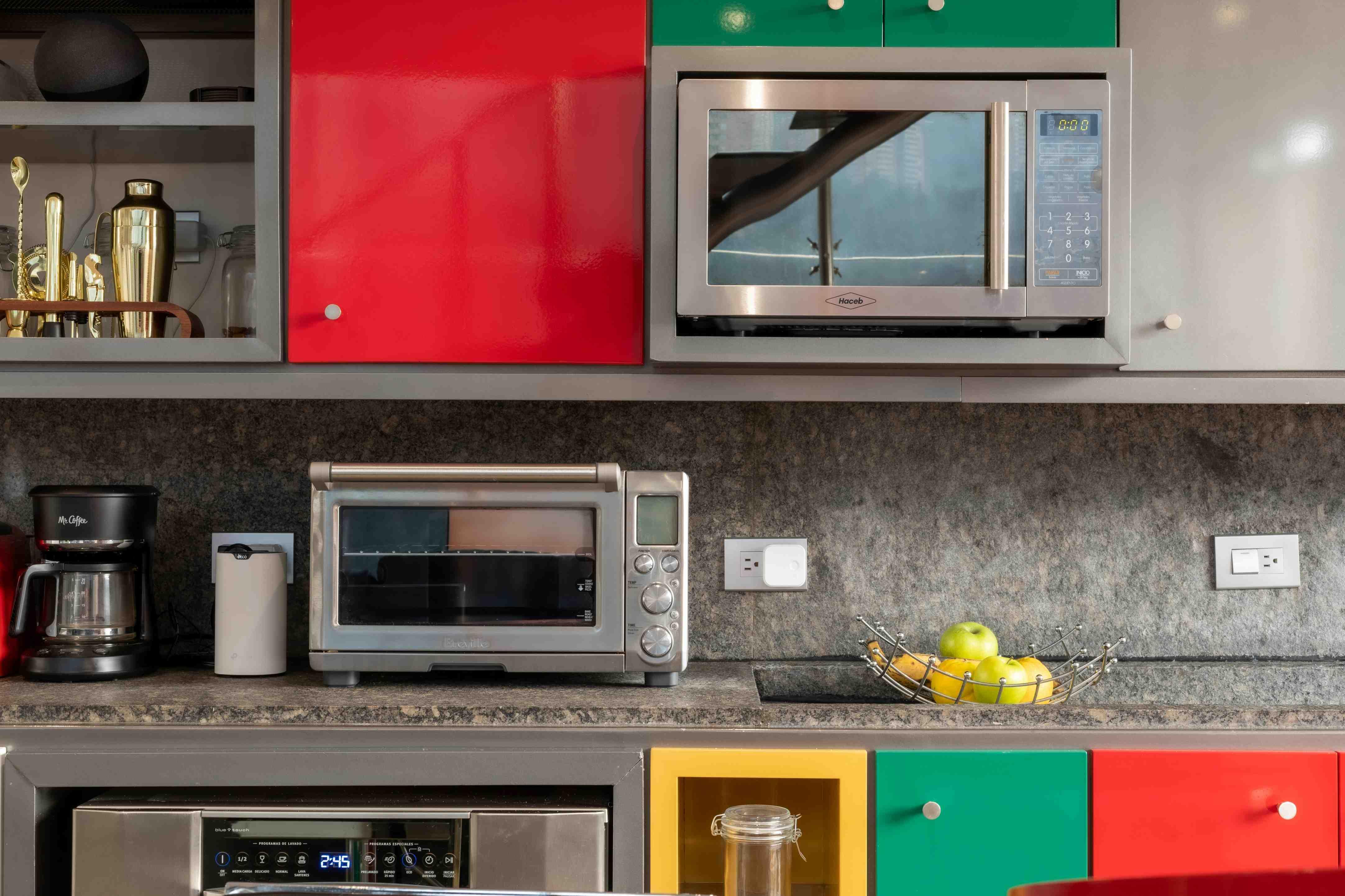 A microwave is pictured embedded in a kitchen alongside other cabinets and a countertop toaster oven.