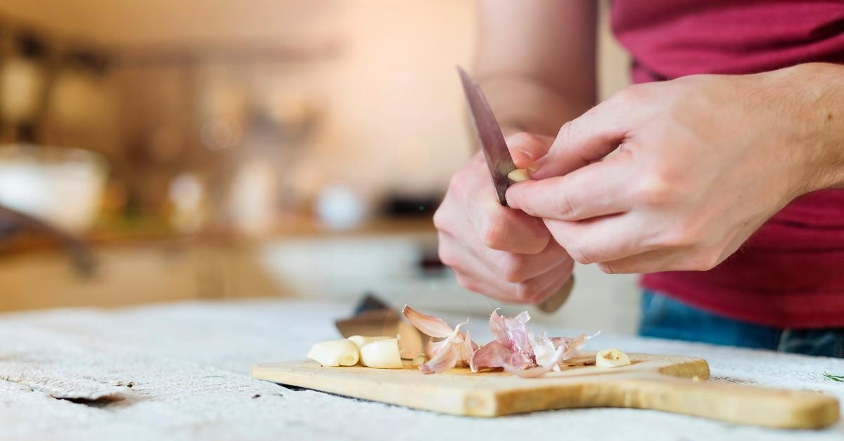 Woman's hands as she cuts and peels garlic cloves