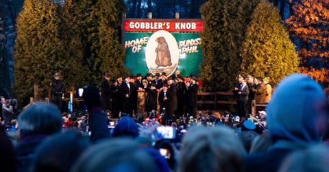 Men wearing top hats and tuxedos surround Punxsutawney Phil on Groundhog Day