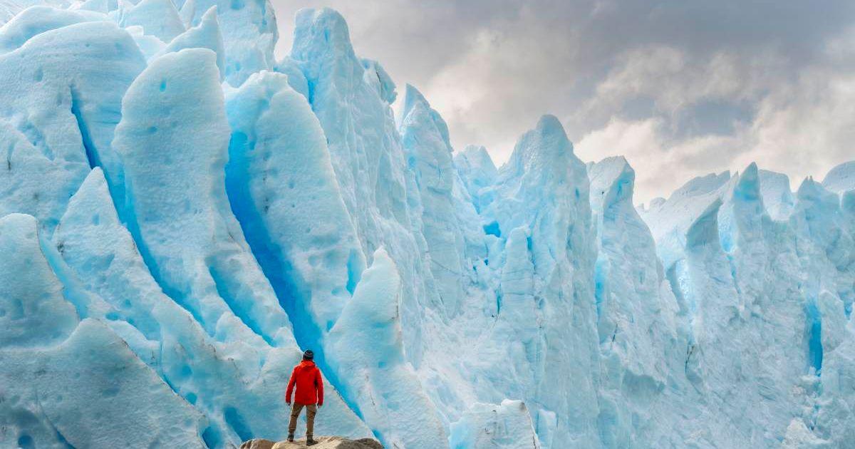 A man is standing in front of a giant ice crevasse. (Representative Cover Image Source: Getty Images | Francesco Vaninetti Photo)