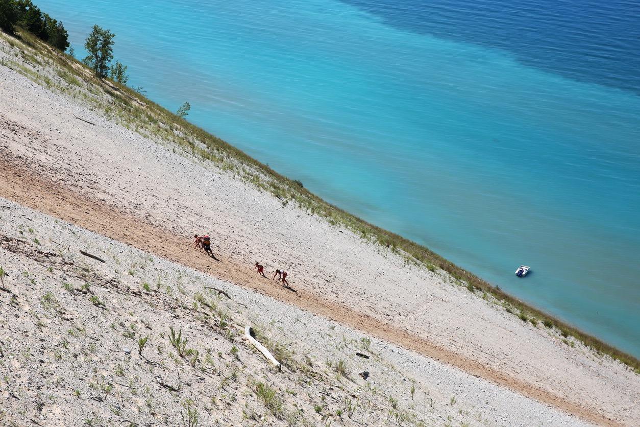 Tourists climbing up an extremely steep sand dune along Lake Michigan.