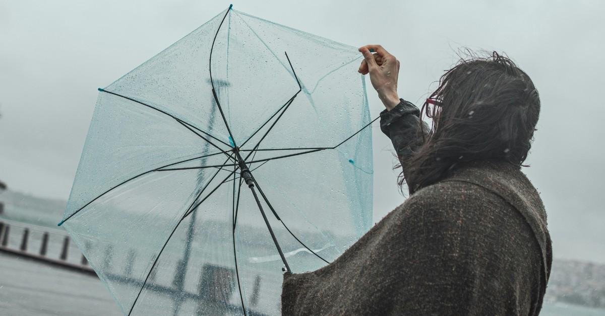 A woman struggles with her umbrella in the rain
