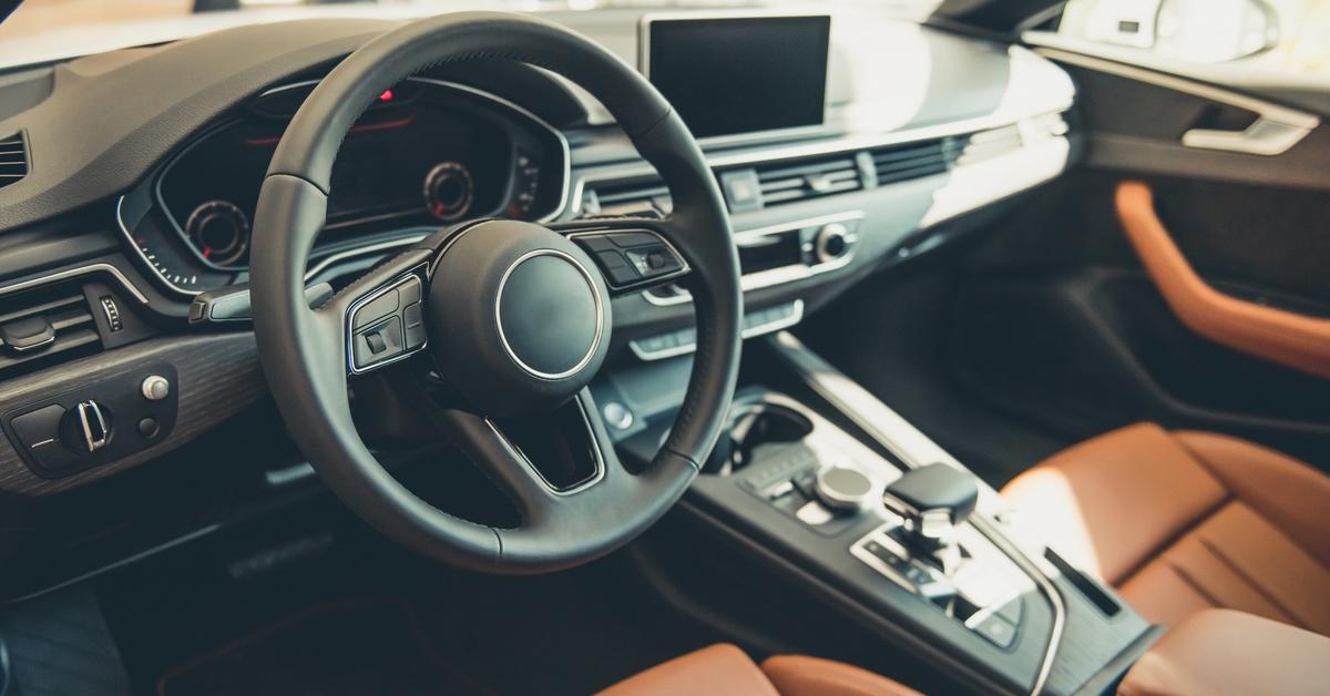 The inside of a brand-new car with leather seats and a black dashboard.