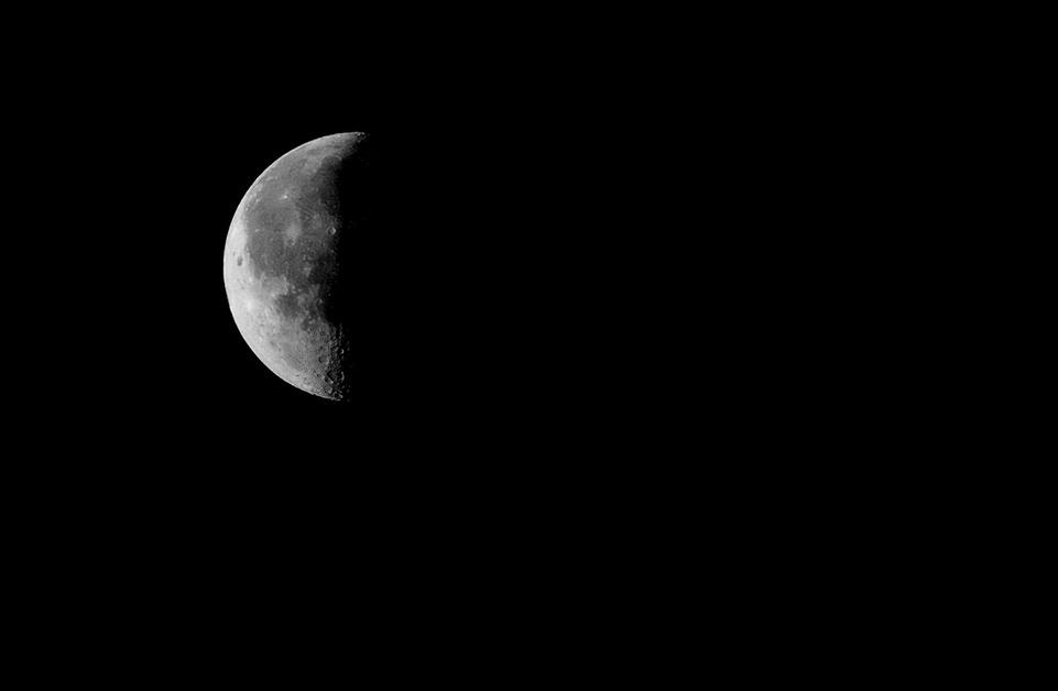 A photo of a third quarter moon in front of a black background. 