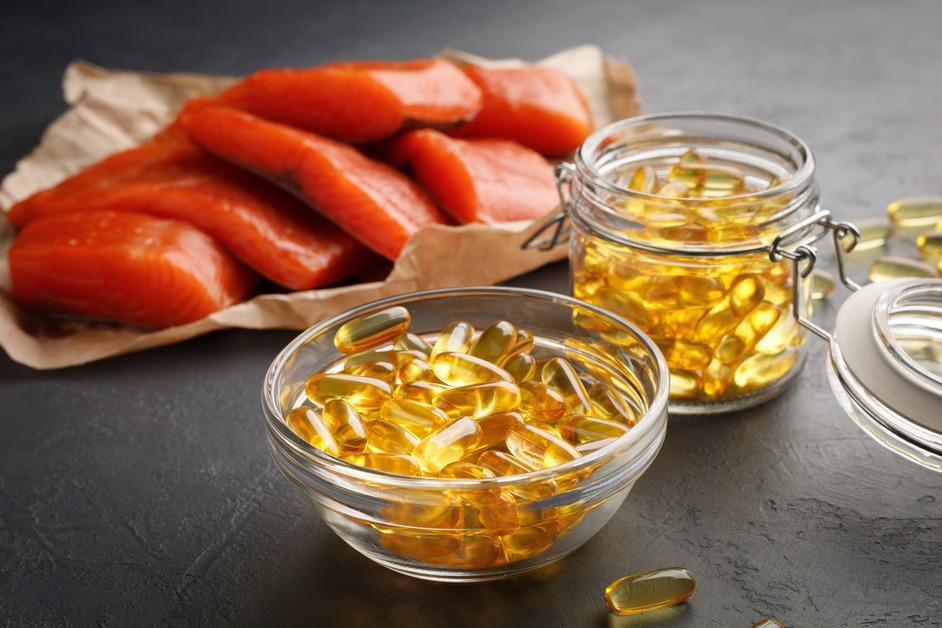 Omega-3 fatty acid capsules sitting next to a pile of salmon.