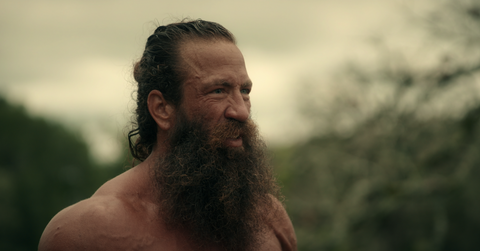 A shirtless Brian Johnson stands outside