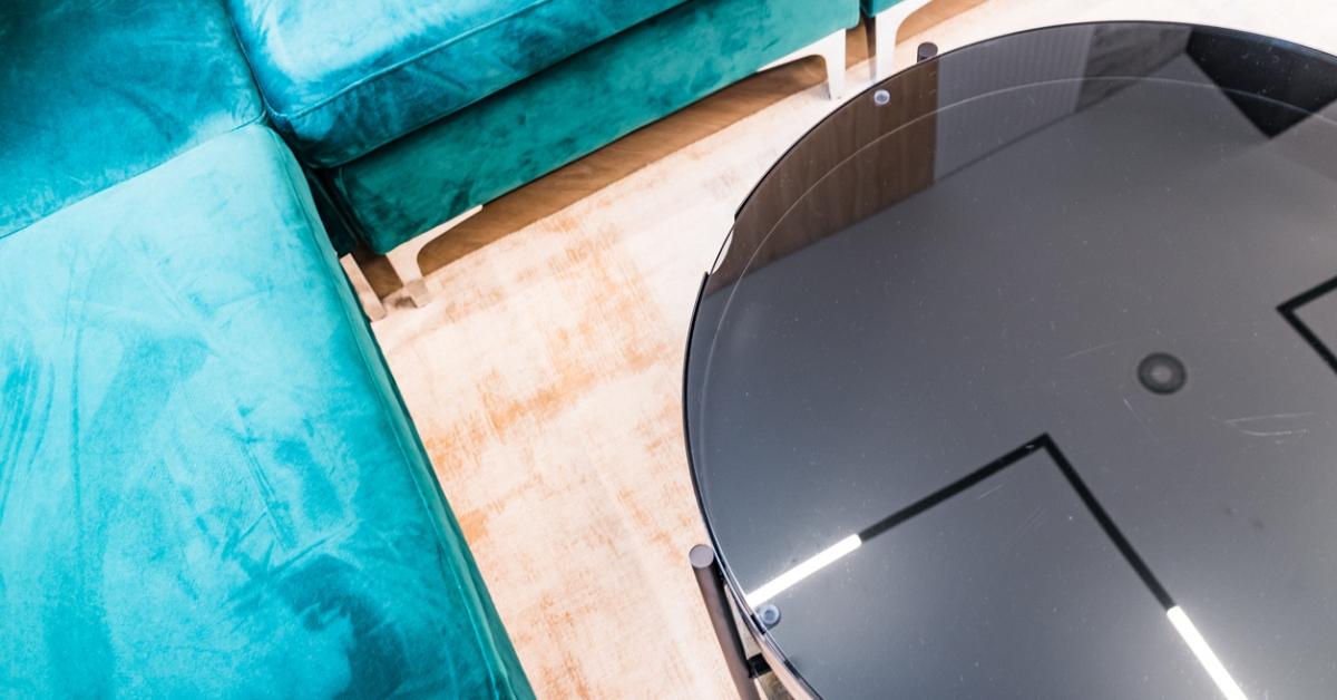 A black glass coffee table and velvet couches. 