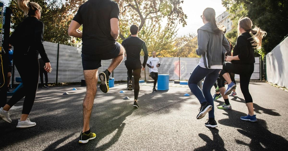 A bunch of people workout together, lifting their legs and stretching