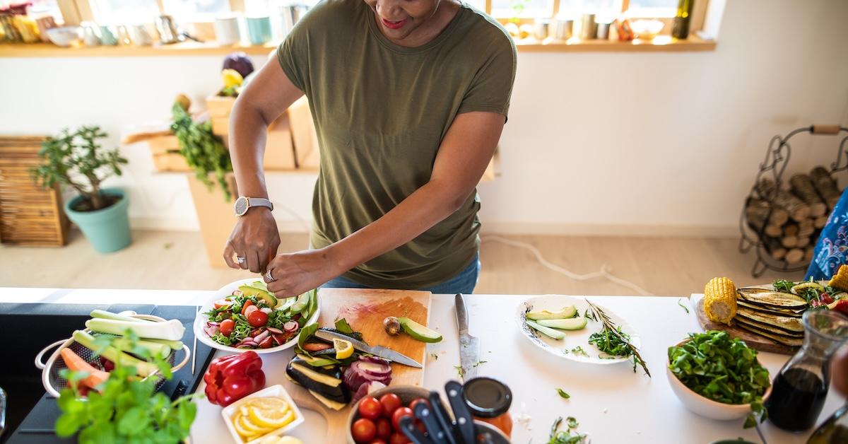 Woman prepares salad and vegetables at kitchen island