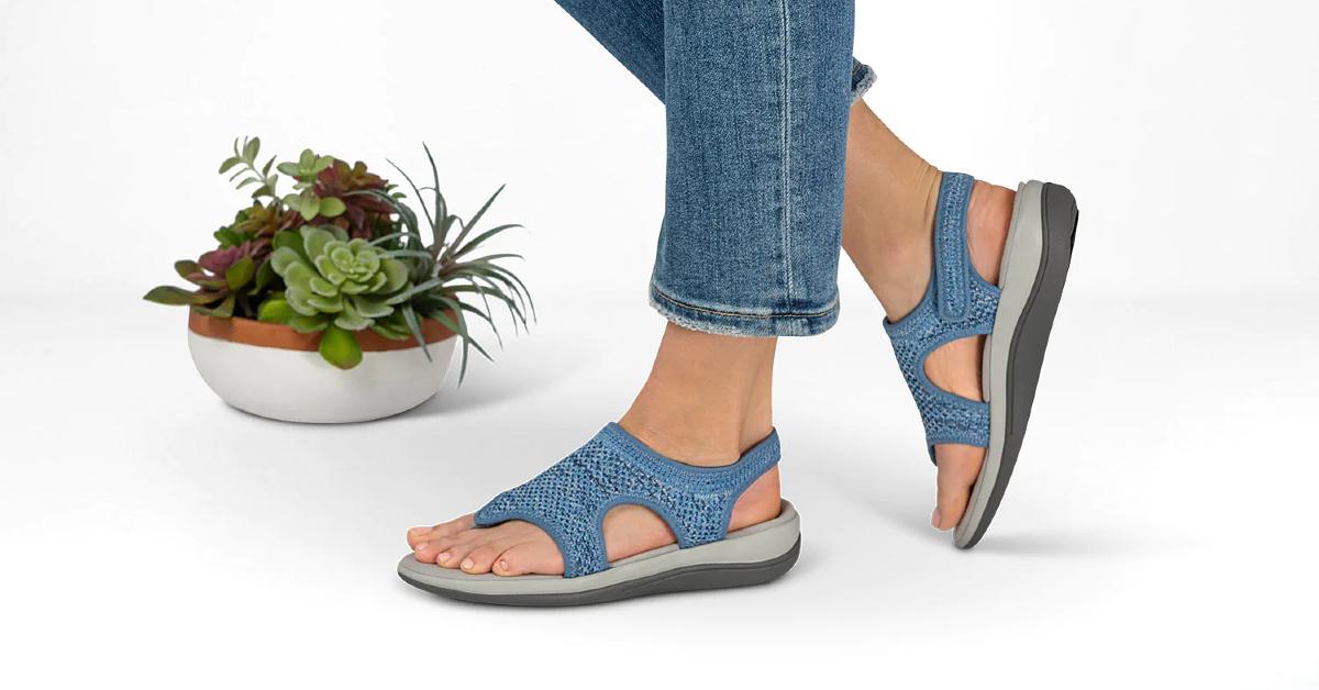 Product photo of a woman's feet wearing Orthofeet Lyra sandals next to a potted succulent plant