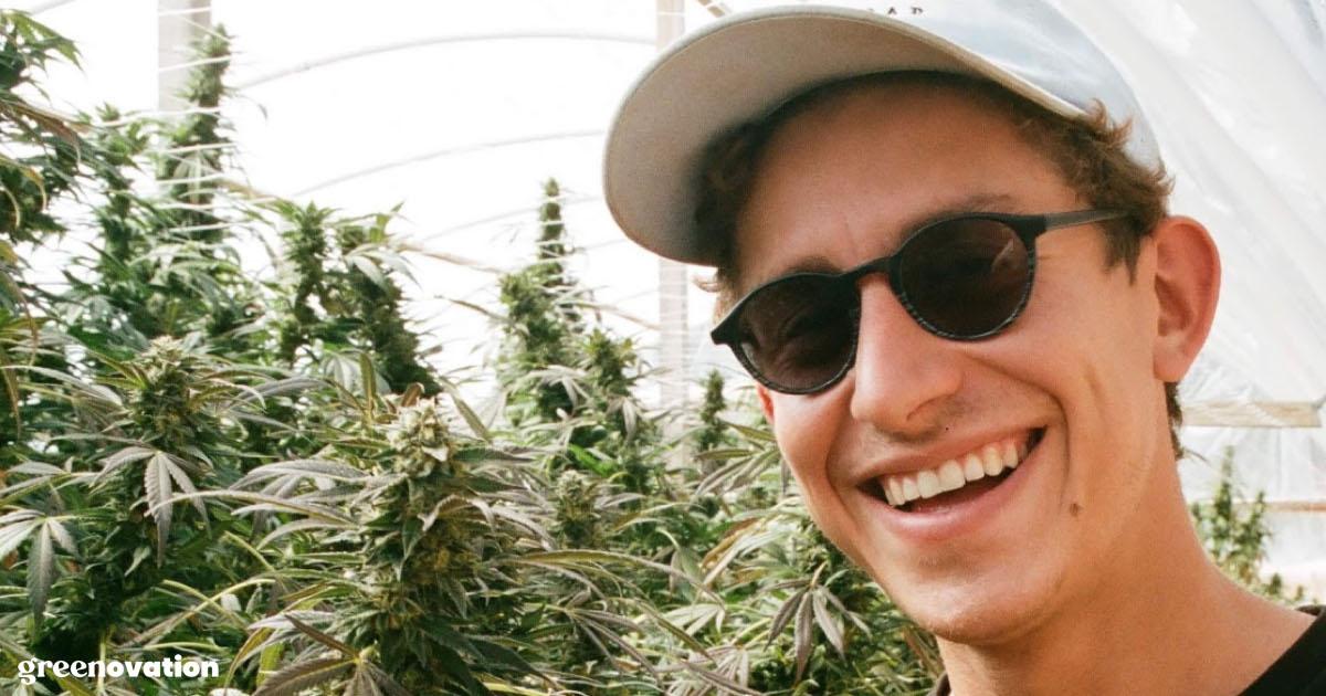 Closeup of Lex Corwin smiling surrounded by cannabis plants in a greenhouse