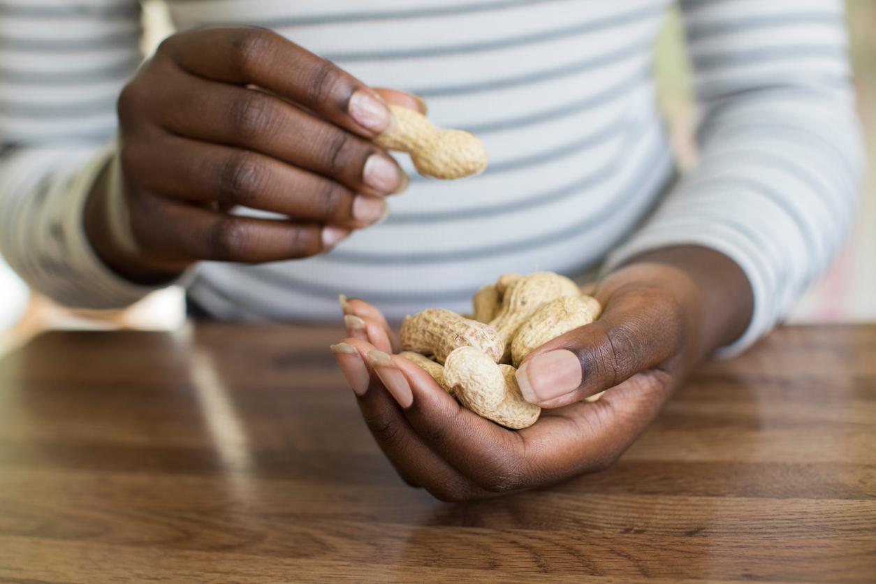 A woman with a handful of peanuts prepares to consume peanuts with their shells on.