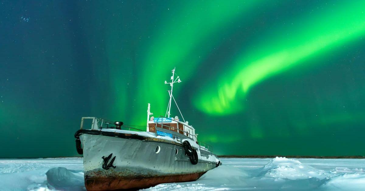 A ship docked on icy waters with the stunning Aurora Borealis lighting up the sky. (Representative Cover Image Source: Pexels | Виктор Куликов)