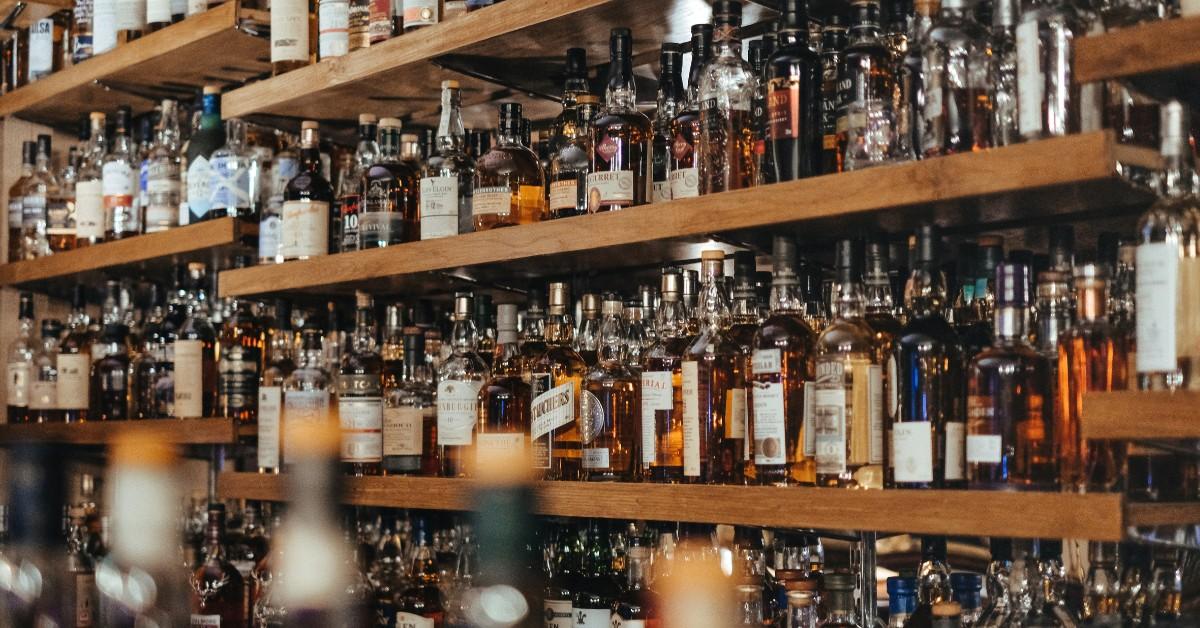 Bottles of liquor sit on a shelf in a bar