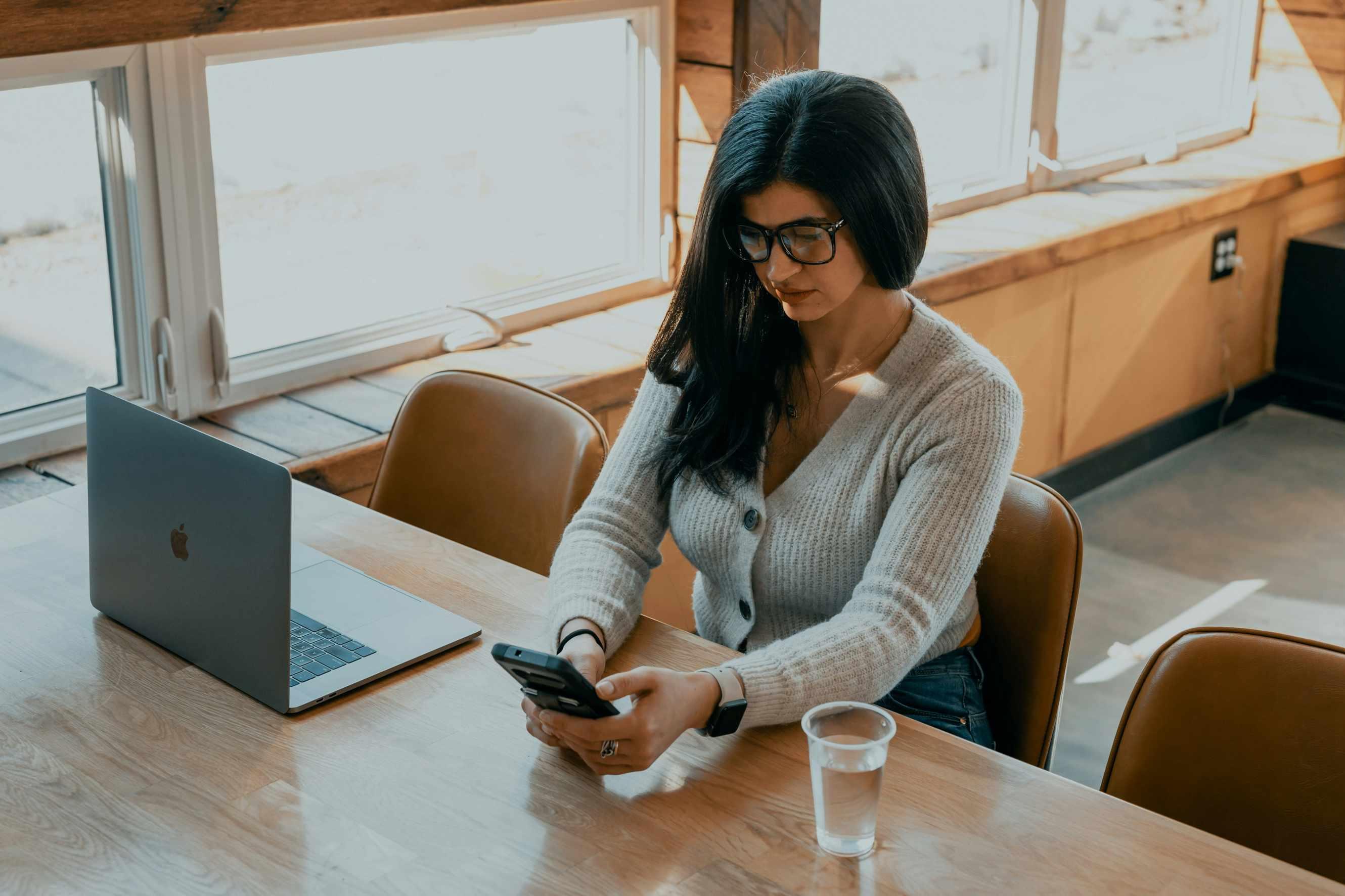 A woman in a gray sweater texts in class.