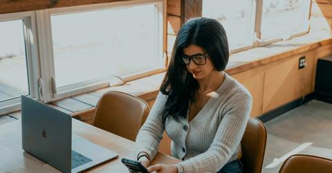 A woman in a gray sweater texts in class.
