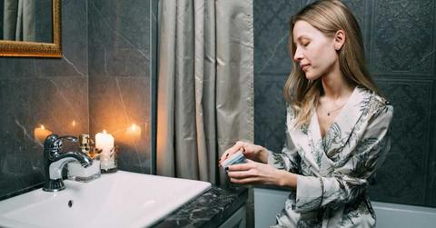 A woman is in her bathroom opening a box of skincare. (Representative Cover Image Source: Pexels | Ivan Smakov)