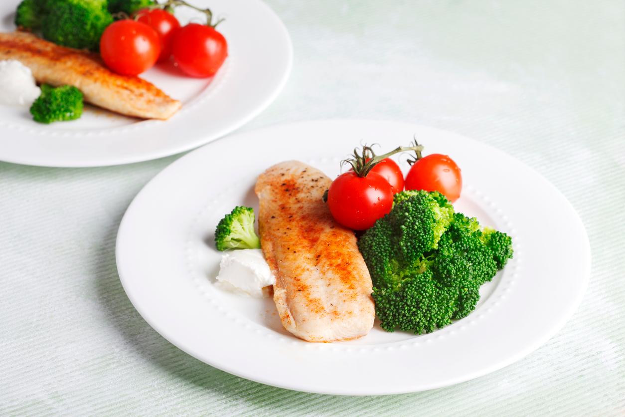 Swai fish on a plate with broccoli and tomatoes.