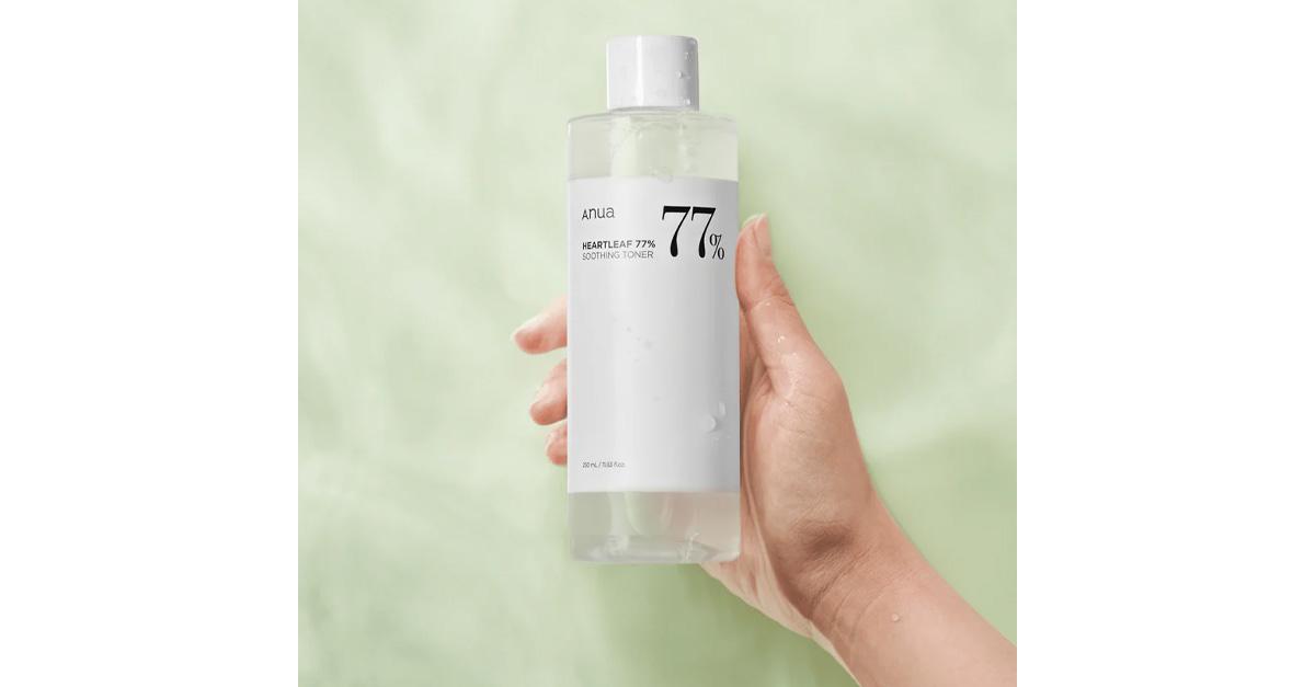 A hand holding Korean skincare toner in a bottle 