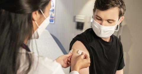 A woman gives a masked man a vaccination