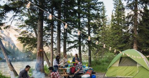 A bunch of friends hanging out and eating at a tent near a lake