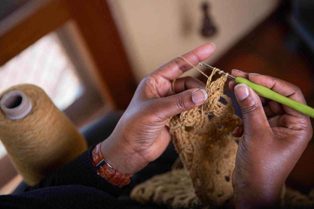 Person crocheting with a small, light green hook and tan yarn.