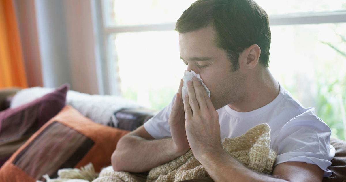 Man blowing nose on couch