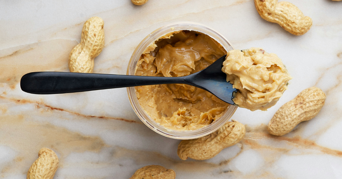 A spoon sits on top of a jar of peanut butter