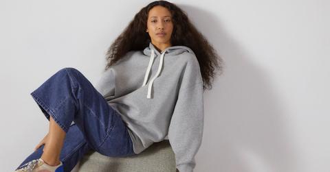 An Everlane model sports jeans and a grey sweatshirt.