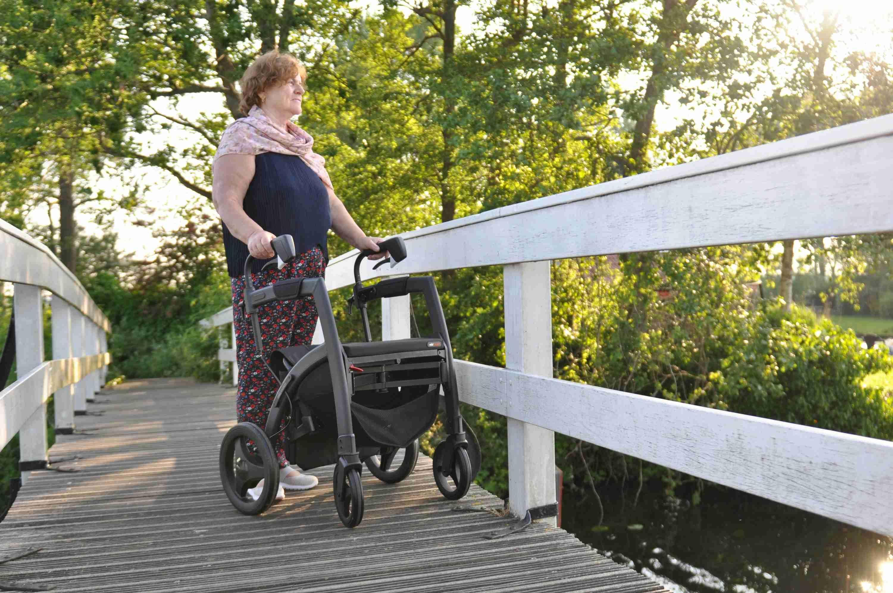 A woman diagnosed with Parkinson's Disease utilizes a mobility aid to walk in nature.
